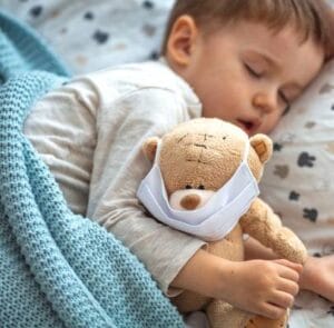 Choroba dziecka. Na zdjęciu chore dziecko leży z misiem